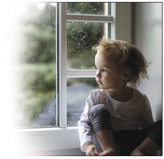 Toddler looking out a window on a rainy day